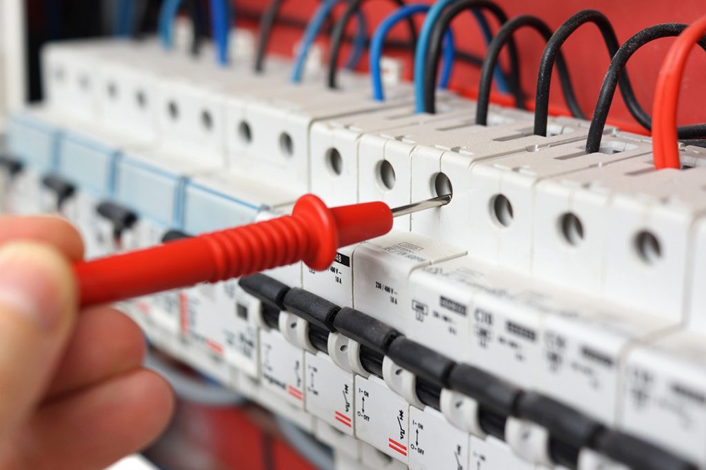 Residential Electricians Hillsboro - Hand of an electrician with multimeter probe at an electrical switchgear cabinet
